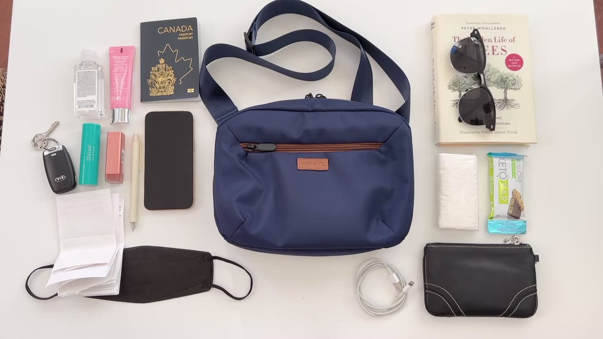 Blue sling bag getting packed with numerous everyday essential and travel items